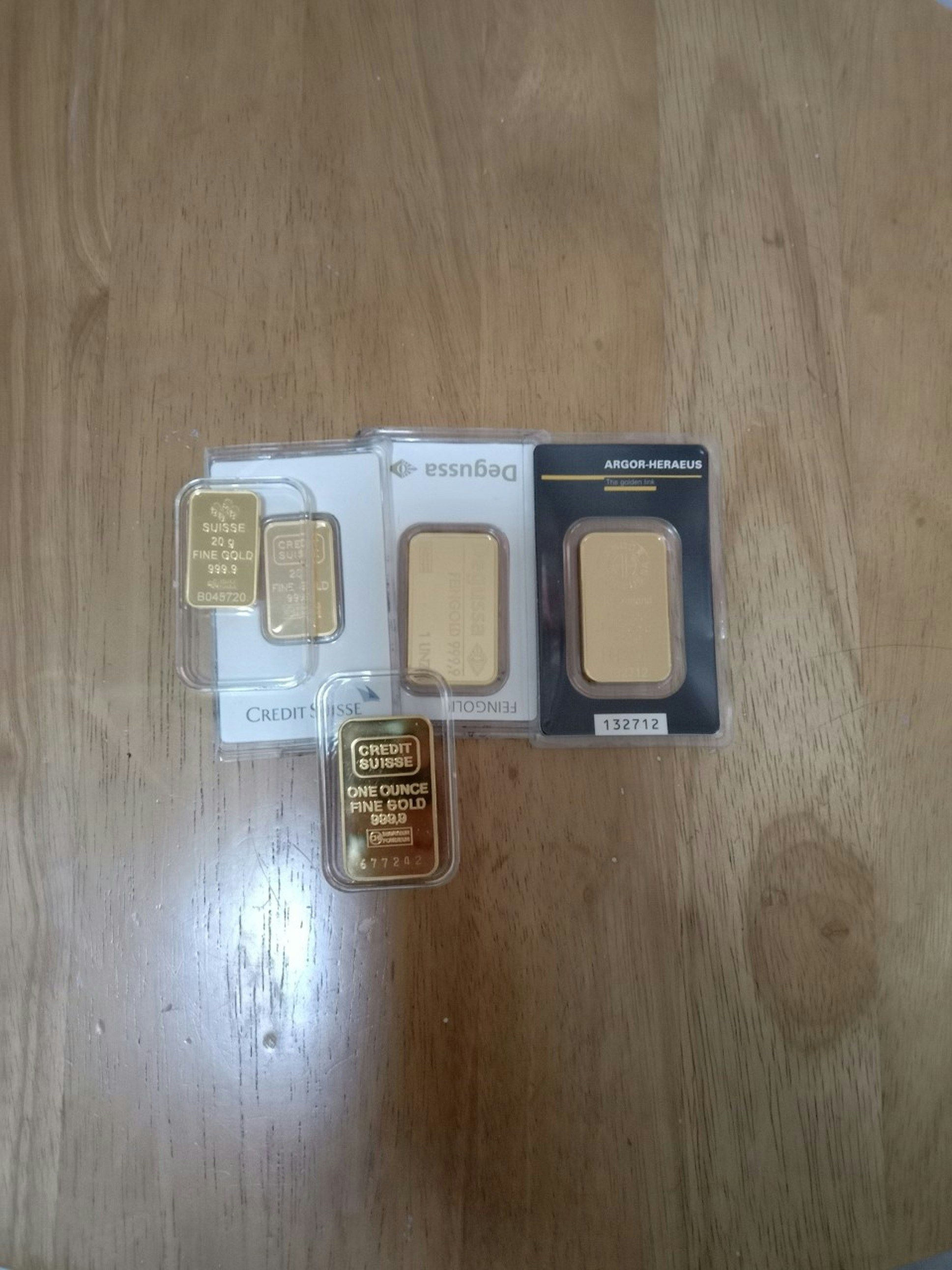 Multiple gold bars stacked beside Ugandan newspaper proof of product context, gold bullion