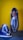 Two handmade, woven leather sandals are displayed against a vibrant yellow wall. The shoes feature a striking blue and white pattern with intricate weaving, showcasing craftsmanship and attention to detail.
