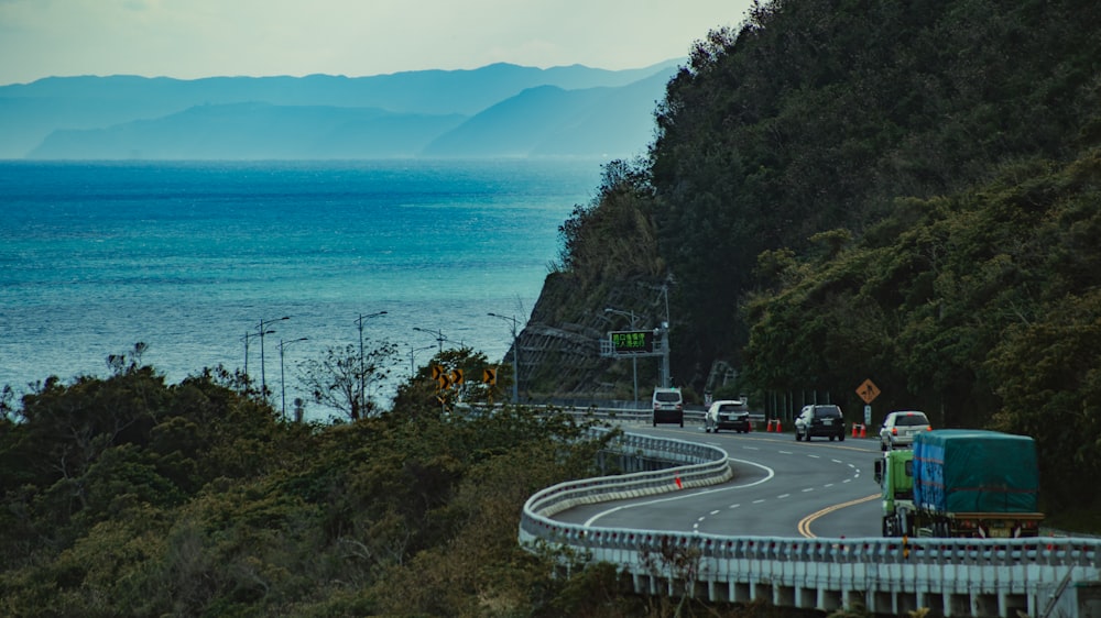 cars on road near trees and body of water during daytime