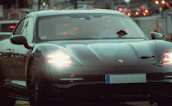 Urban night driving scene featuring a modern car with glowing headlights cutting through the city streets.