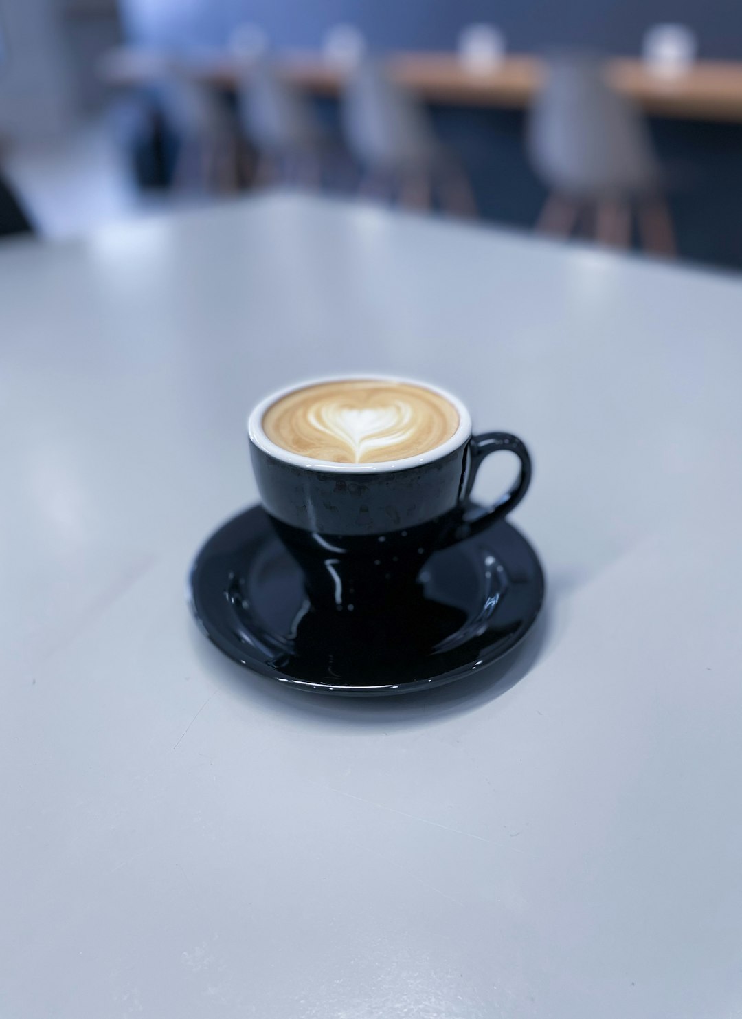 black ceramic cup with coffee on black saucer