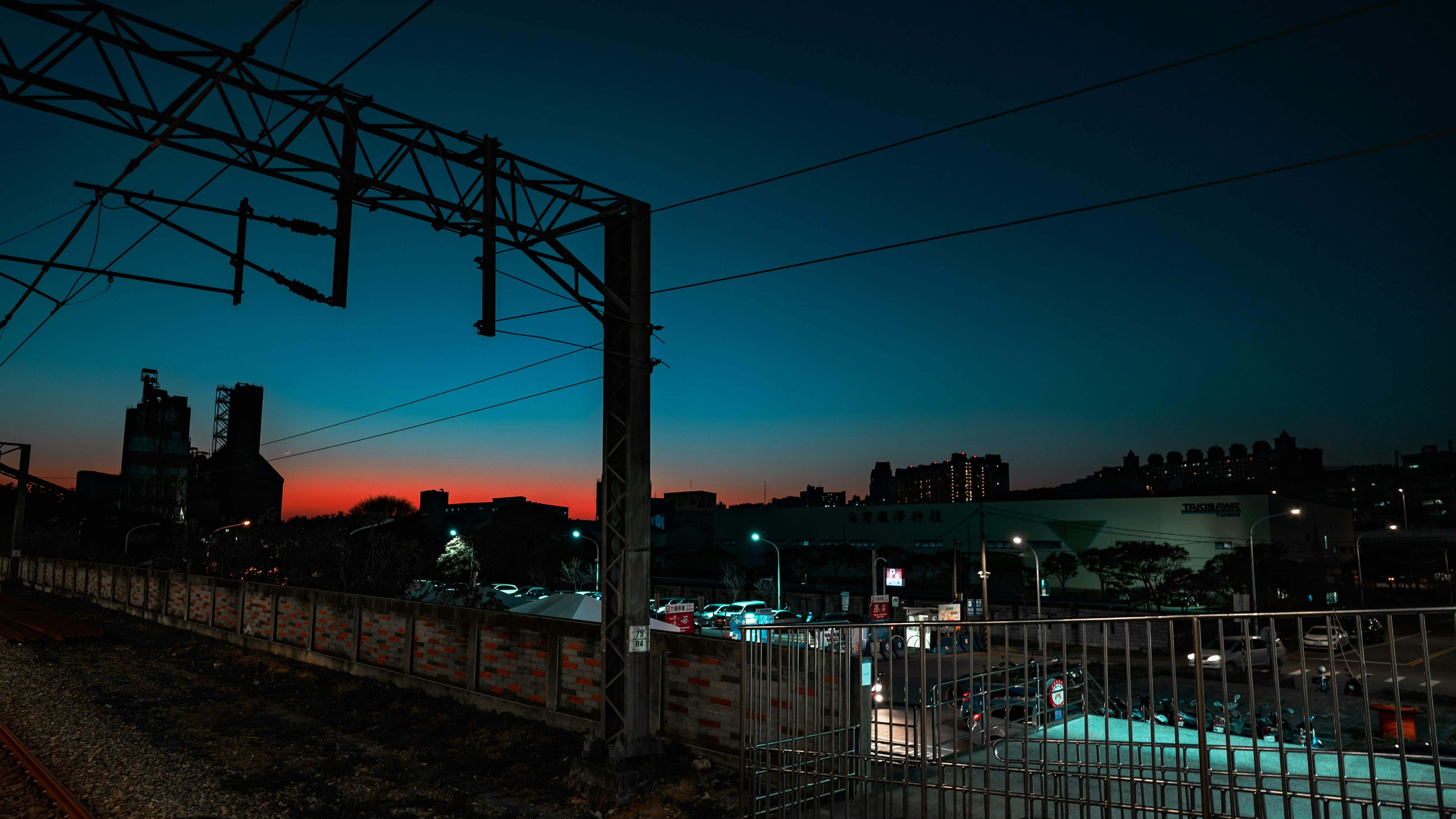 Driver and passenger in a convertible electric car with the roof down, cruising toward the sunset on an open road