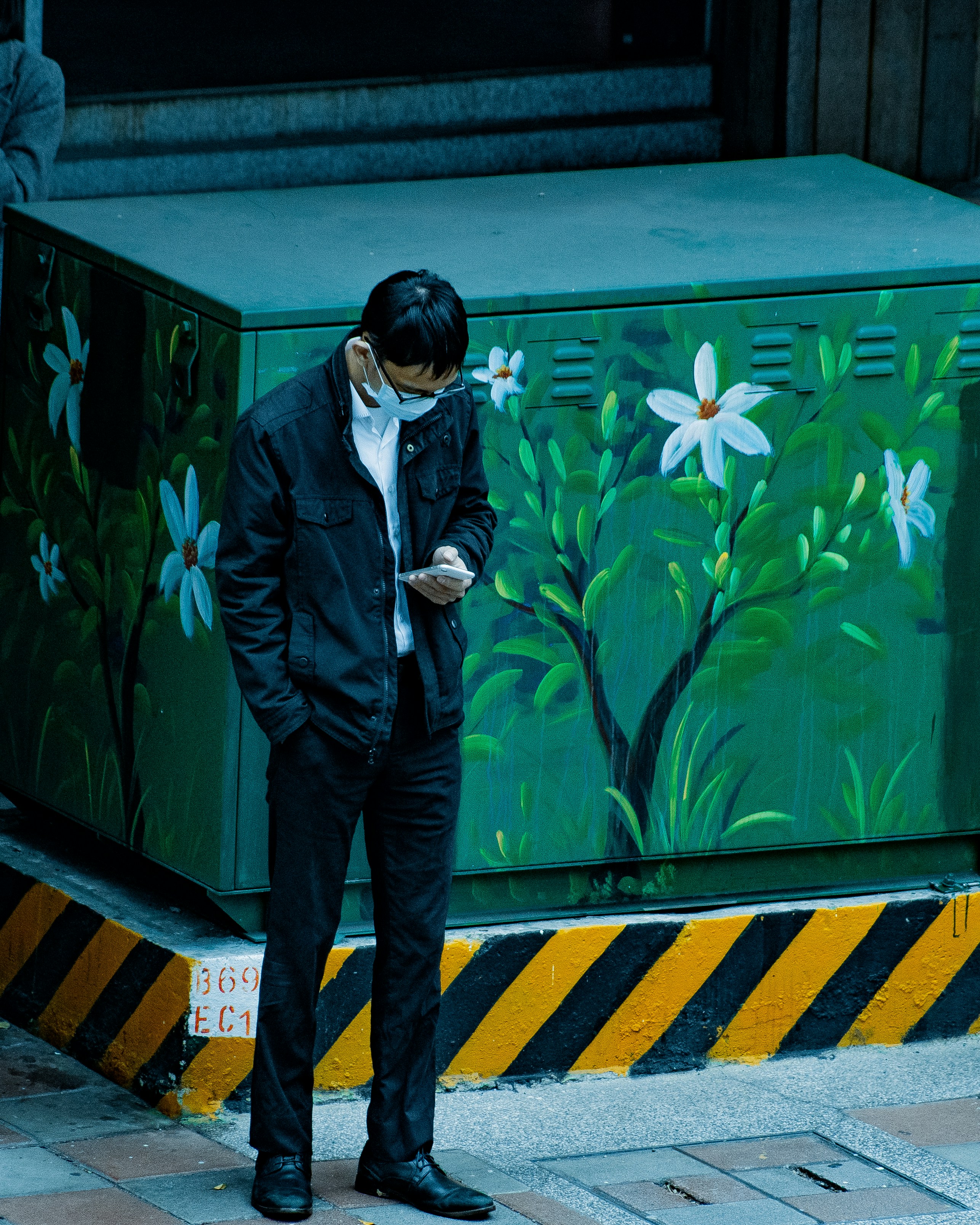 Homme en costume noir debout à côté d’un mur vert