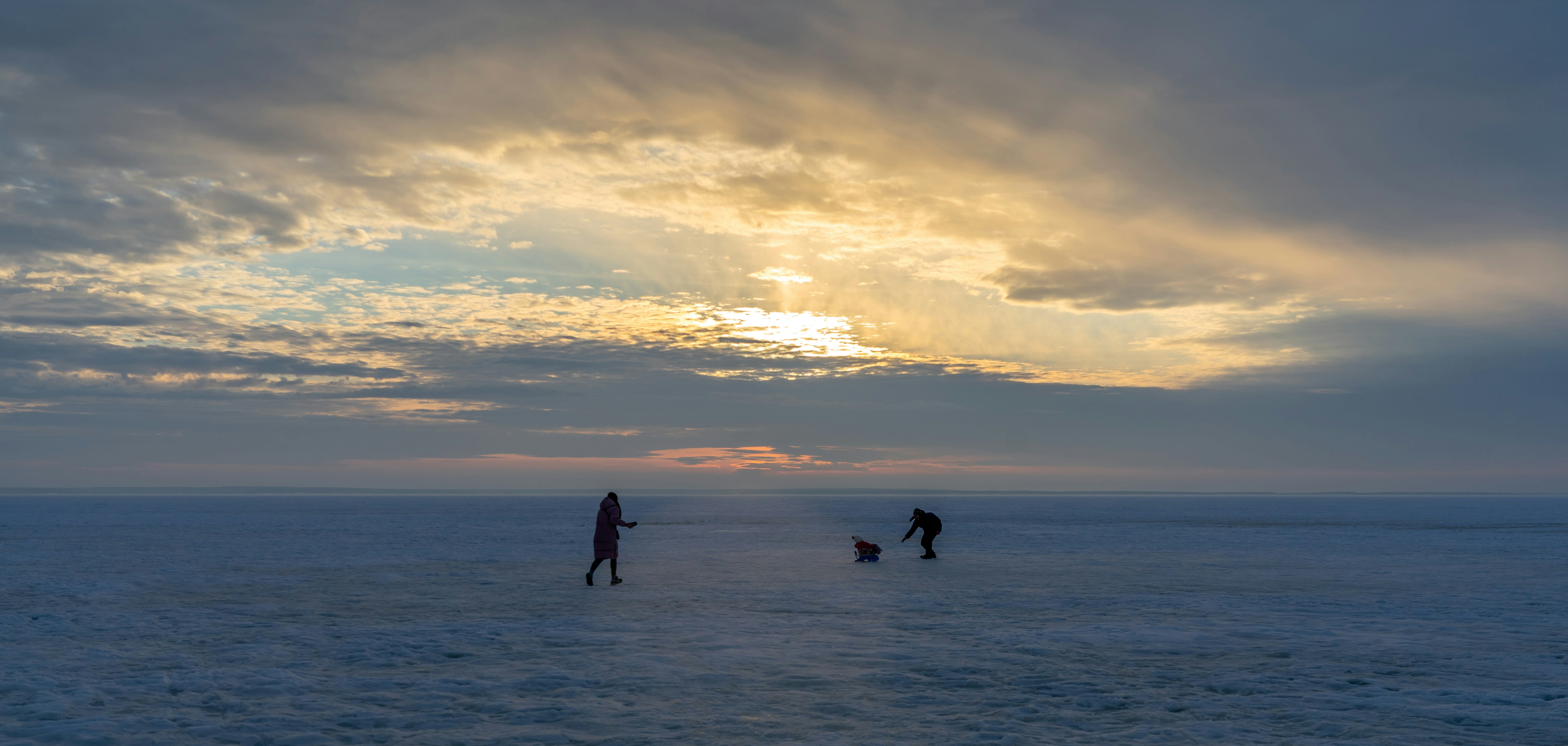 silhouette of 2 people walking on beach during sunset