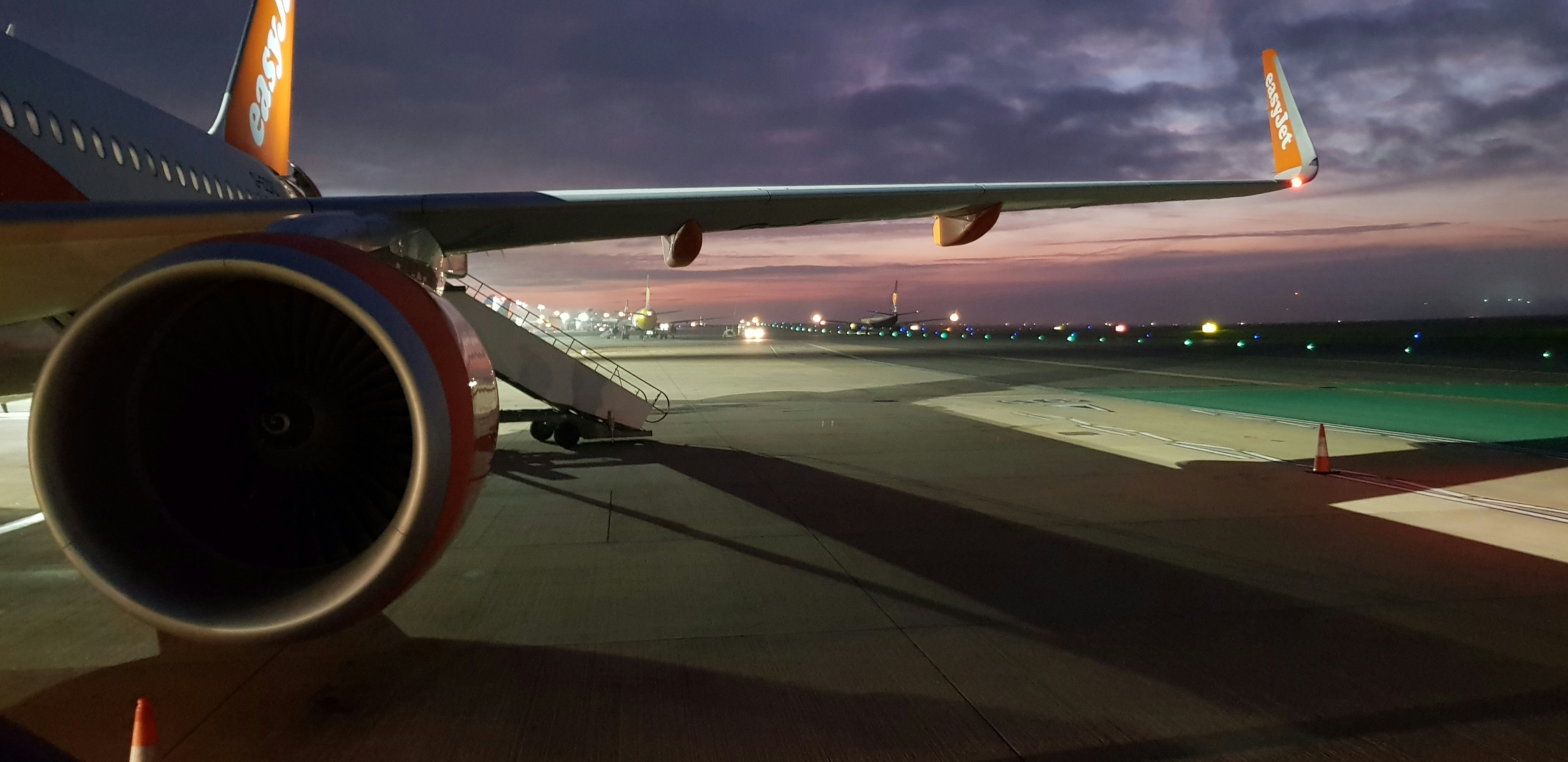 Wide-body aircraft wing and engine on airport tarmac at twilight, atmospheric low-key lighting