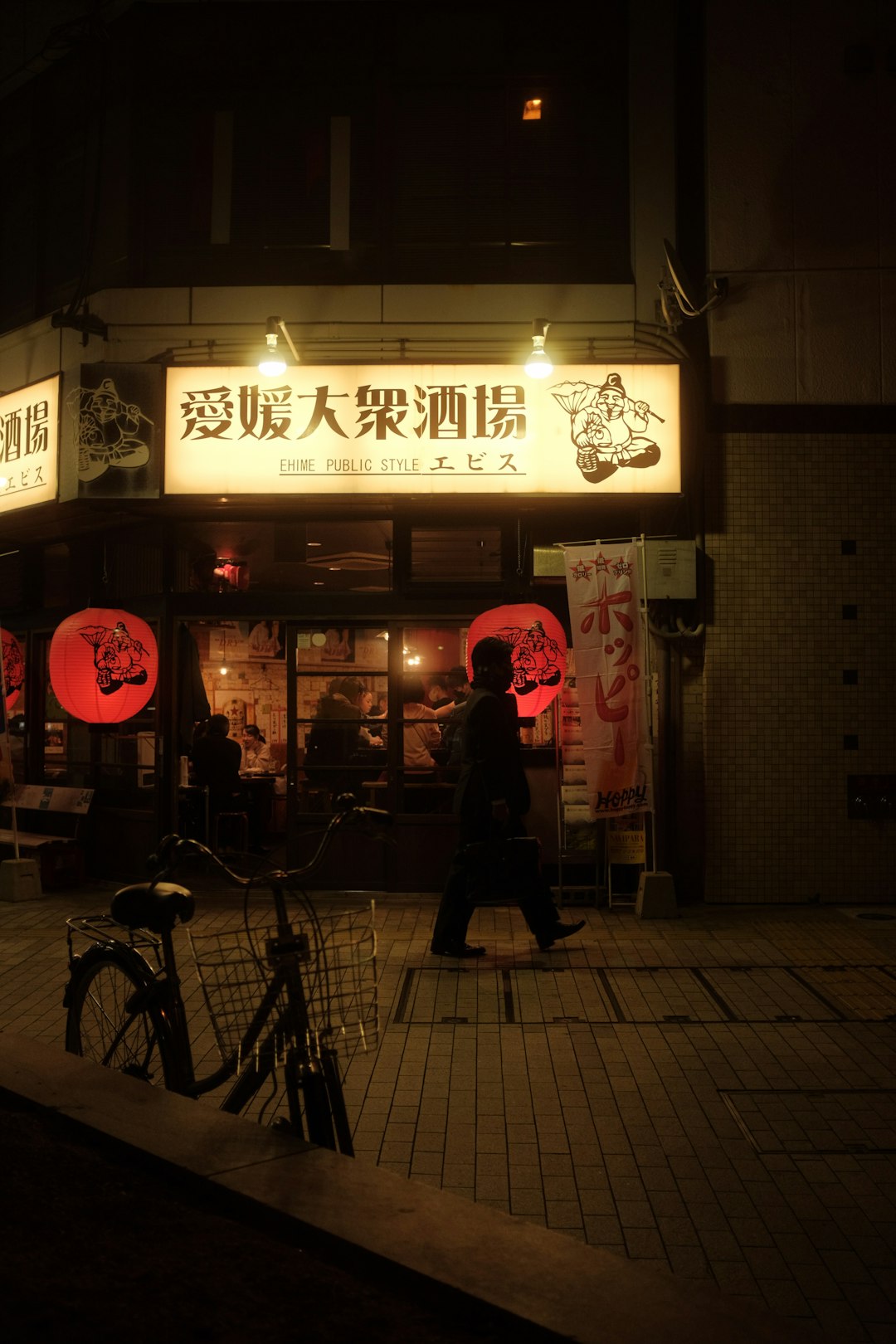 man in black jacket standing near store during night time