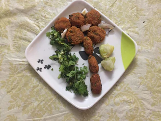 A colorful plate of crispy vegetable pakoras garnished with fresh coriander and lemon wedges.