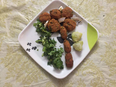 A colorful plate of crispy vegetable pakoras garnished with fresh coriander and lemon wedges.