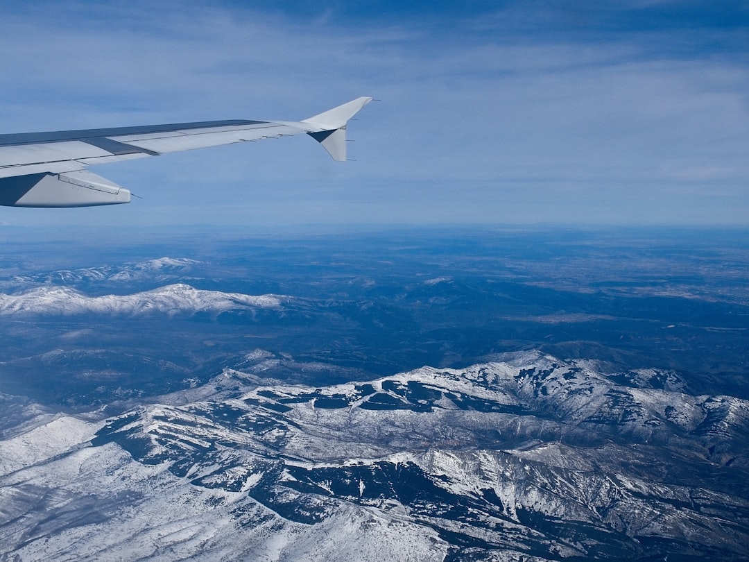 white airplane wing over snow covered mountains during daytime