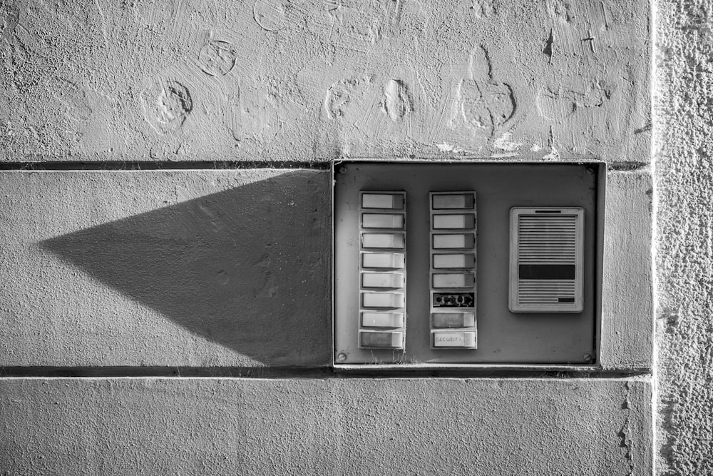 gray scale photo of a wall mounted telephone booth