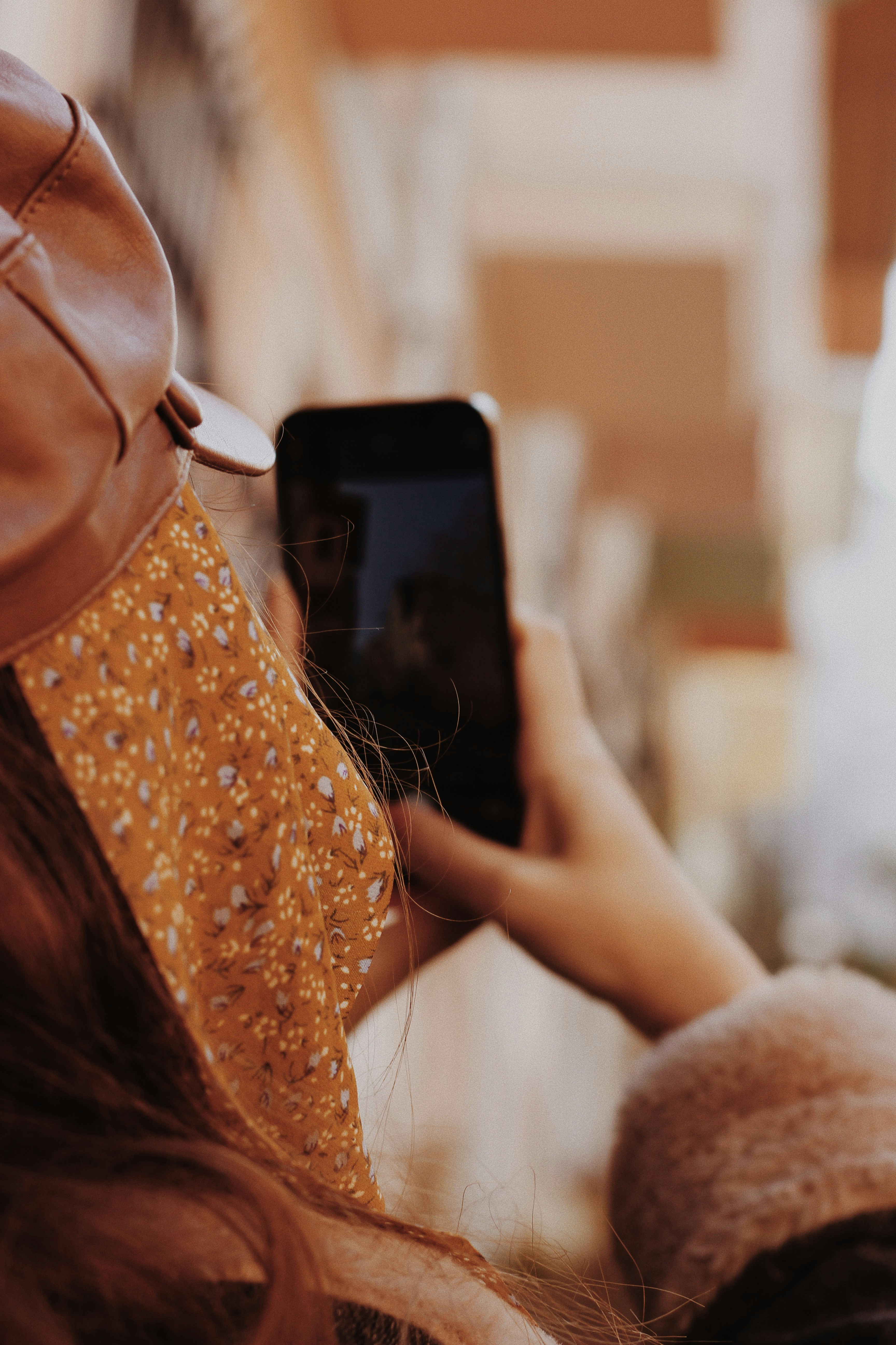 woman in orange and white floral tank top holding black smartphone