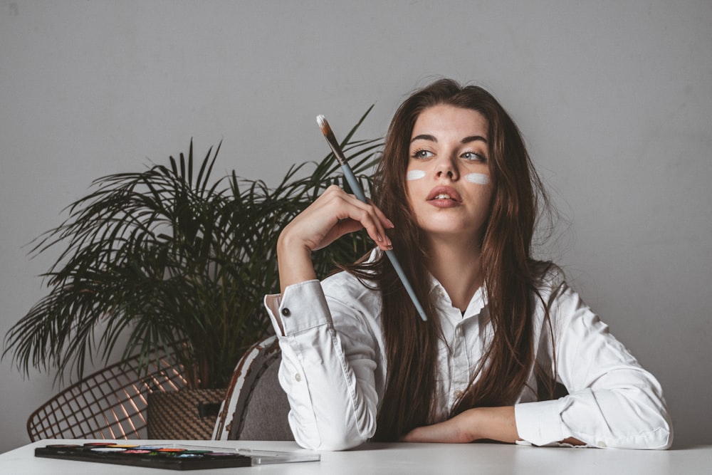 woman in white blazer holding pen