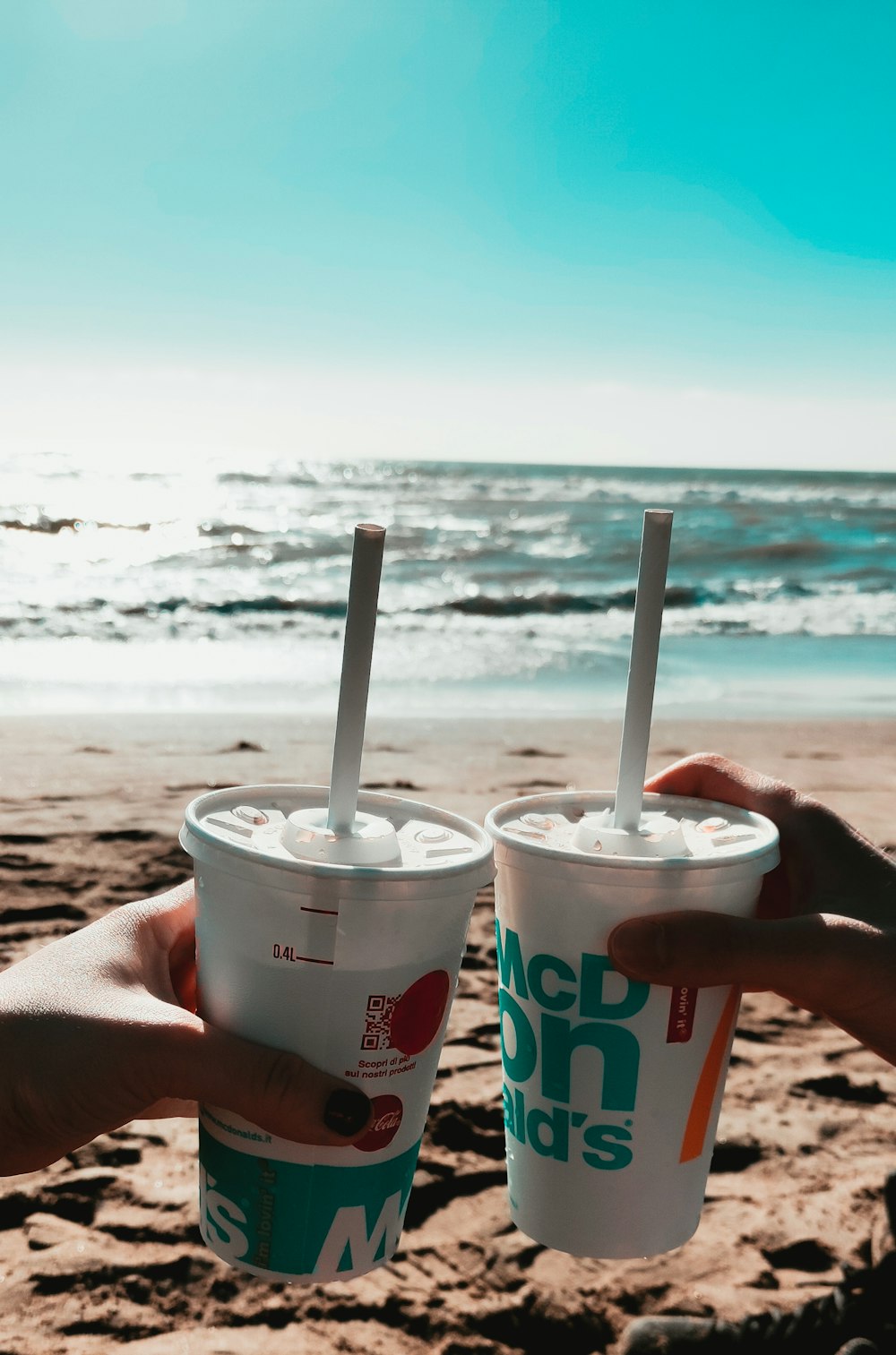 person holding white and red mcdonalds disposable cup on beach during daytime
