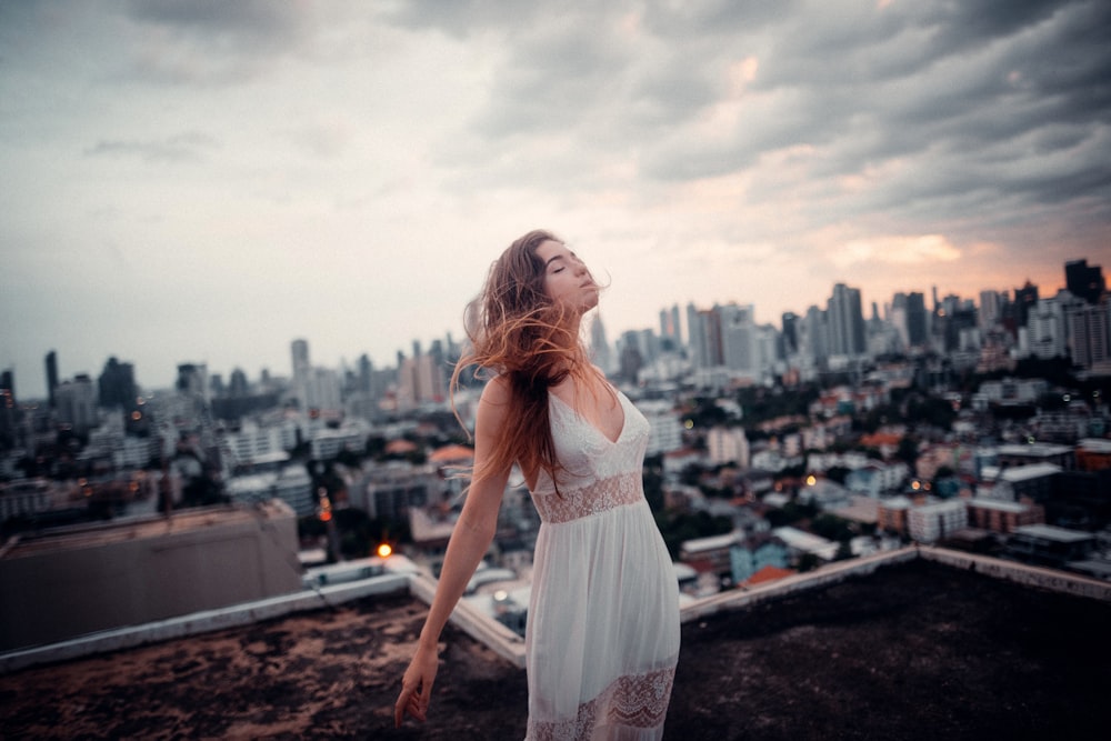 mulher no vestido branco que está em pé no solo marrom durante o dia