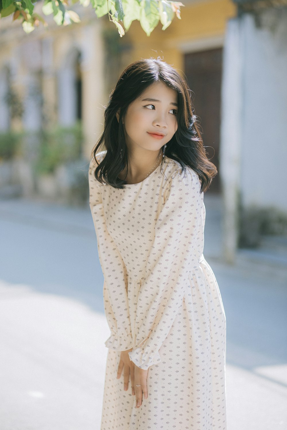 woman in white and yellow polka dot dress standing on snow covered ground during daytime