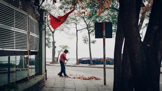 A team member blowing leaves off a driveway in a sunny setting.