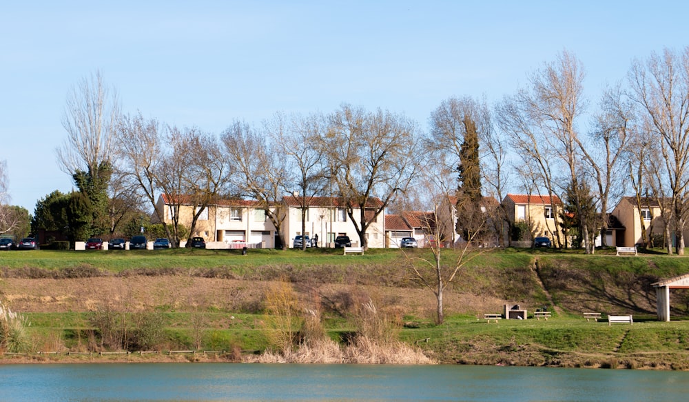 Maison blanche et brune près des arbres verts et du plan d’eau pendant la journée