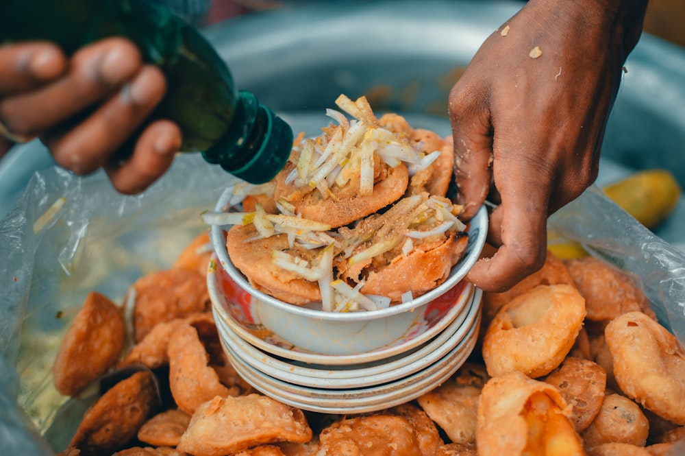 person holding white ceramic bowl with fried food
