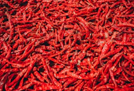 Close-up of loba's rich red chili paste with fresh chili peppers and herbs artfully arranged around it.
