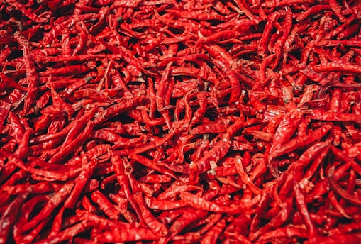 Close-up of bright red chillies piled in a rustic wooden crate.