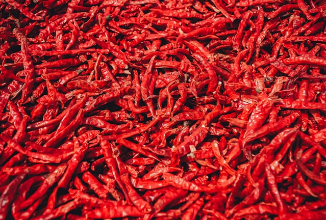 Close-up of bright red dry whole chillies neatly arranged in a woven basket.