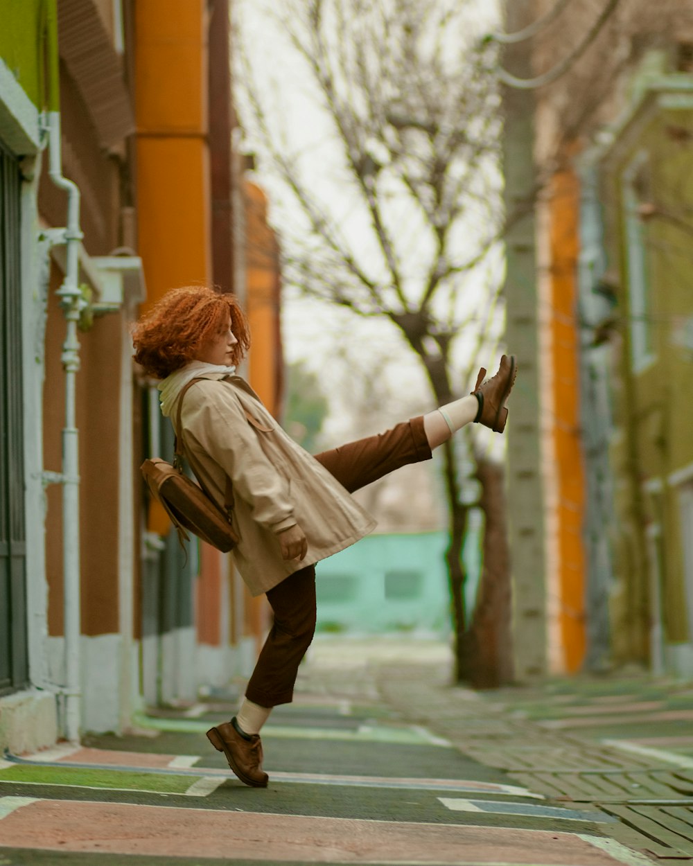 woman in brown jacket and black pants walking on sidewalk during daytime