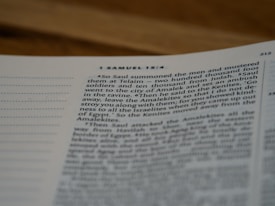 A close-up of an open book displaying a passage of text. The visible page number is 212, and the text includes a portion from a biblical scripture, specifically from 1 Samuel 15:4. The text discusses Saul summoning men and foot soldiers. The image focuses on the text while the book is positioned on a flat surface.