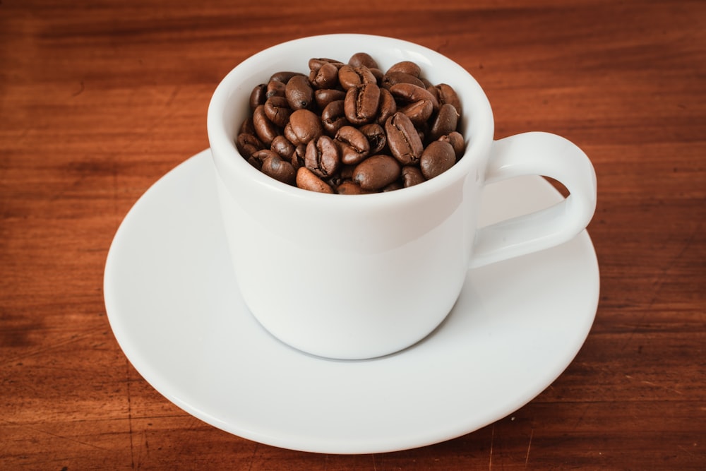 coffee beans in white ceramic mug on white ceramic saucer
