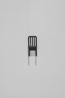 Minimalist black garment draped over a modern chair in a dimly lit room emphasizing texture.