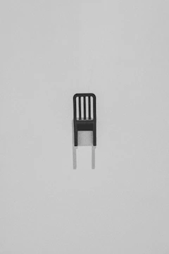 Minimalist black and white photo of a lone chair casting a long shadow on a white floor.