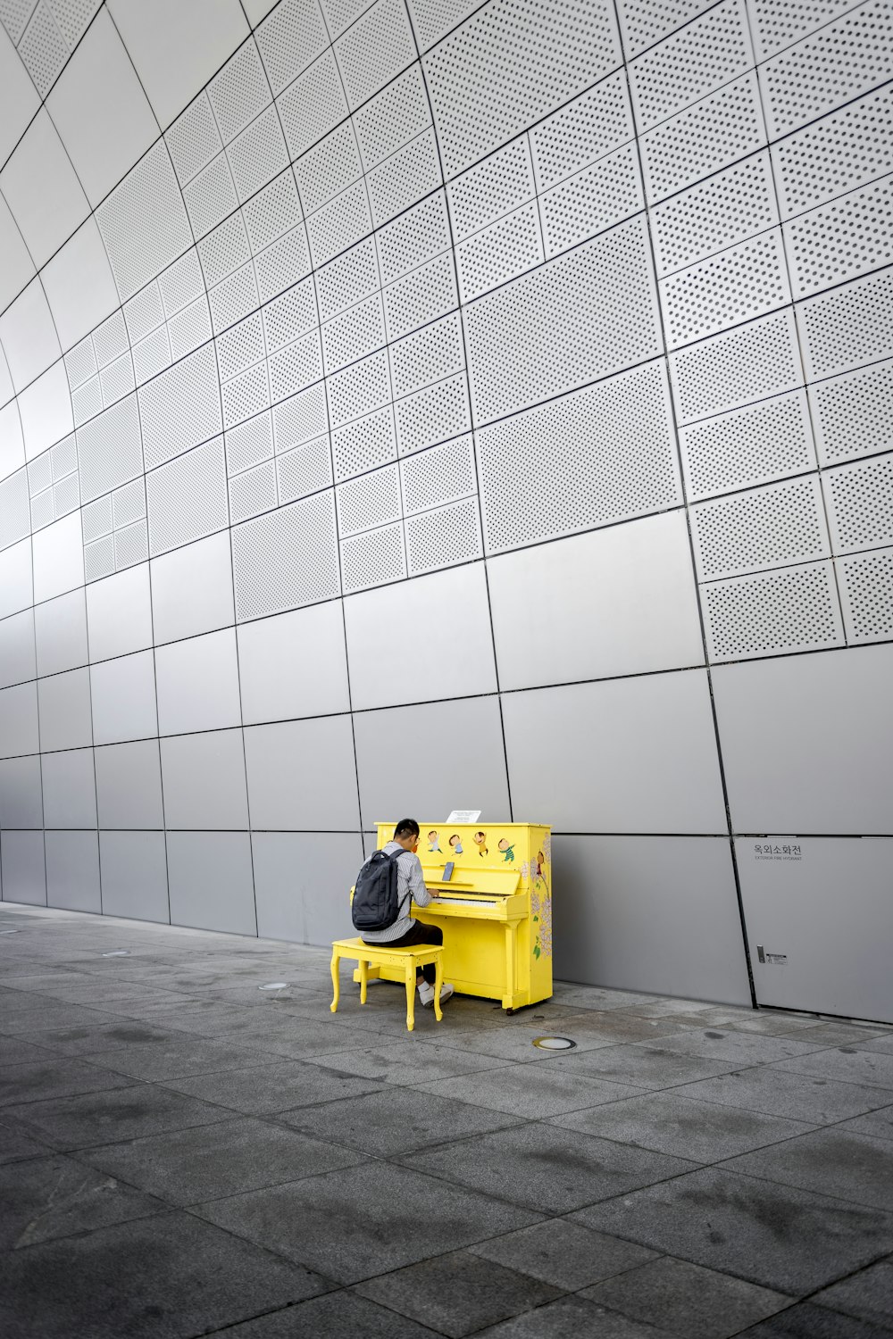 man in yellow jacket sitting on yellow plastic chair