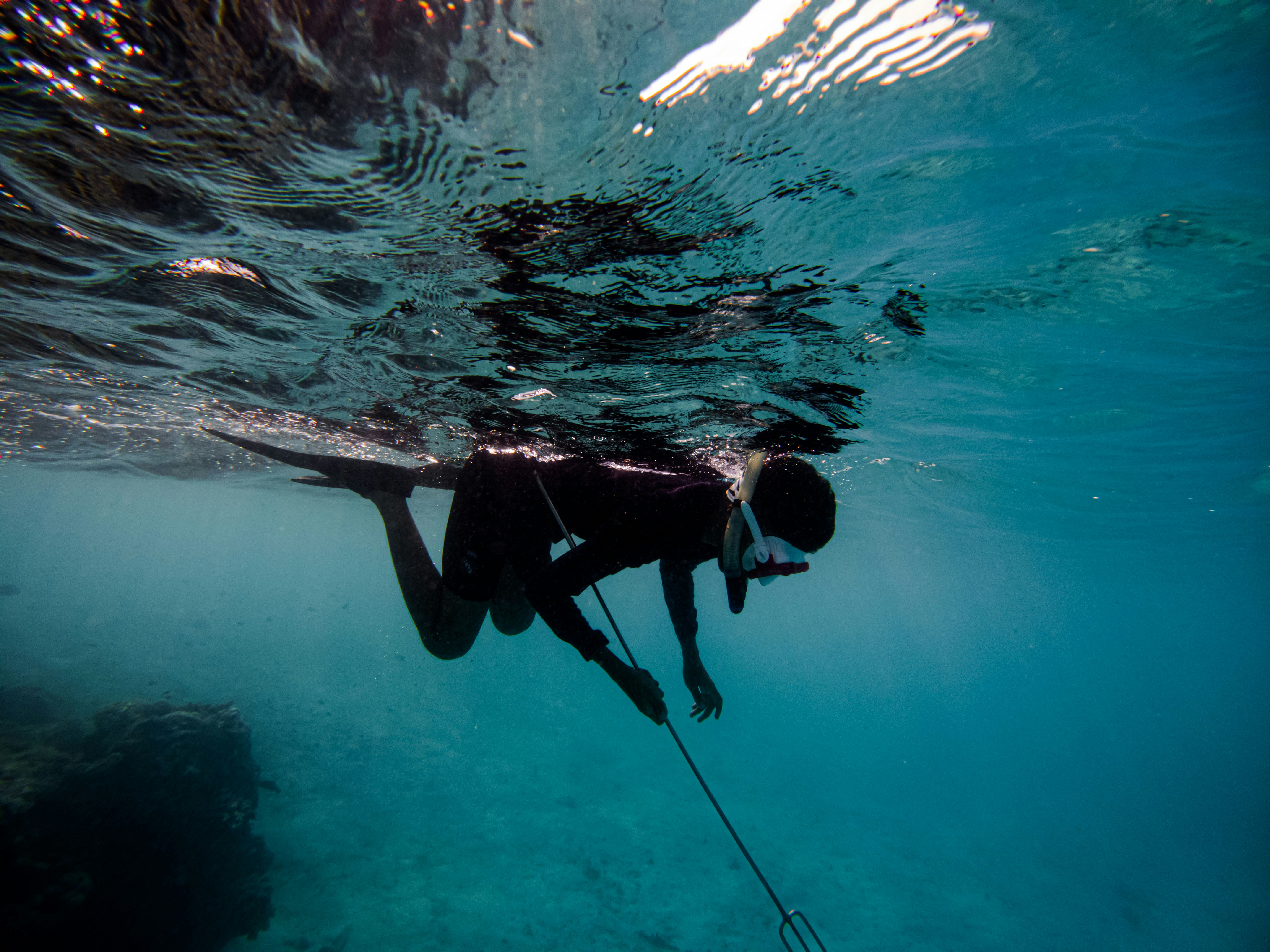man in black wet suit swimming in water