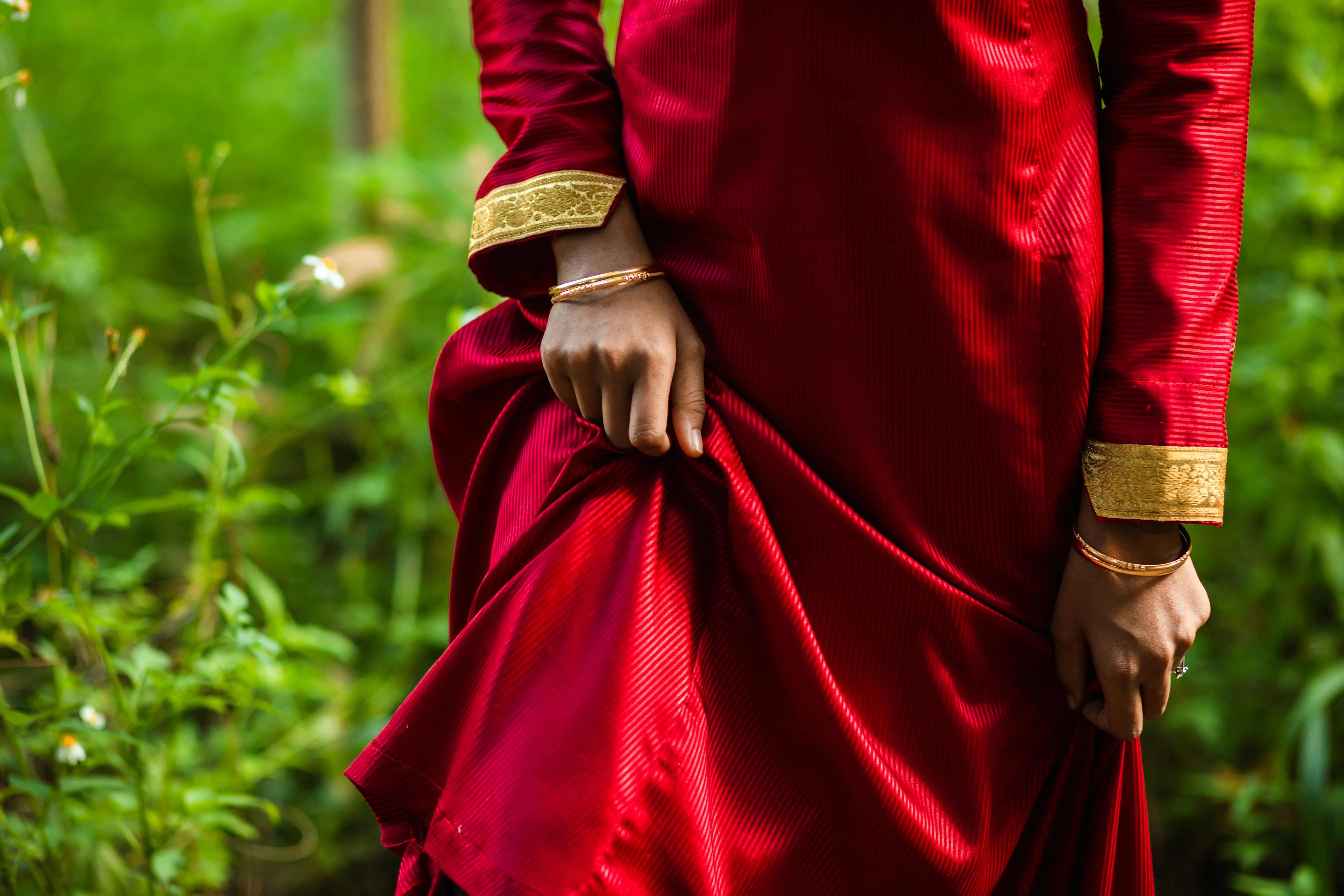 person in red long sleeve dress wearing gold and black hat