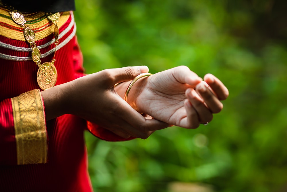 person in red long sleeve shirt holding hands with gold ring