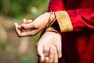 person in red long sleeve shirt holding hands with gold ring