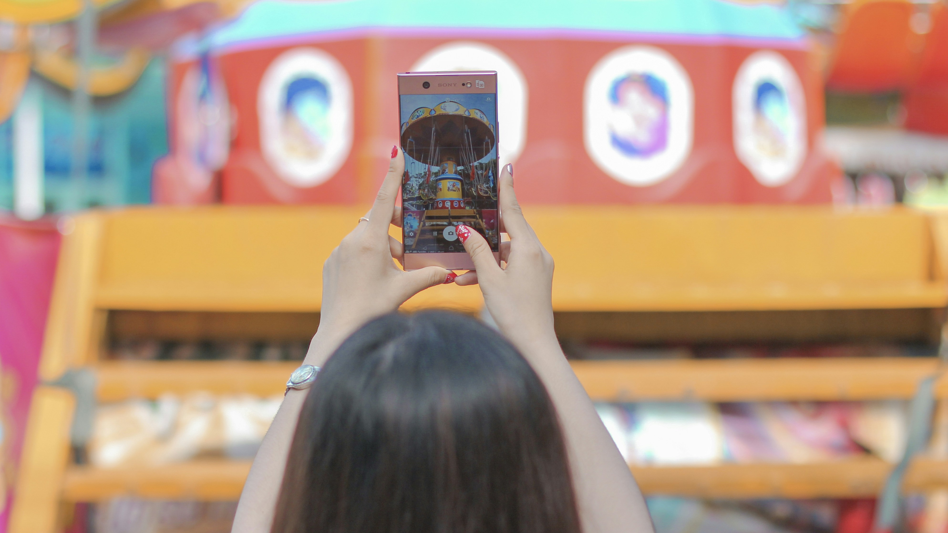 Wanita memegang iPhone 6 mengambil foto bangunan kuning dan merah