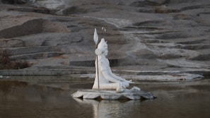 A peaceful statue of Lord Shiva meditating by a riverside at dawn