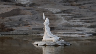 A peaceful statue of Lord Shiva meditating by a riverside at dawn