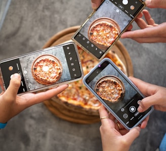 person holding black smartphone taking photo of pizza