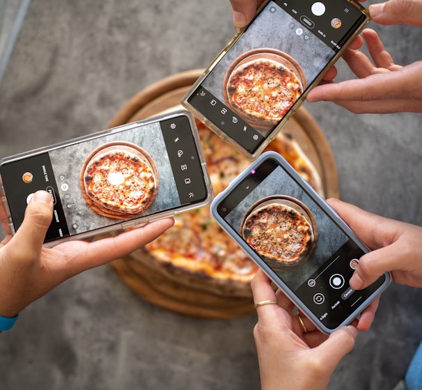 person holding black smartphone taking photo of pizza