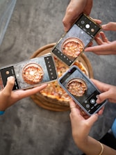 person holding black smartphone taking photo of pizza