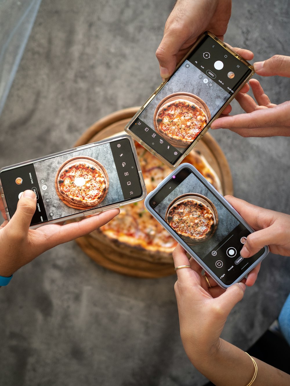 Person mit schwarzem Smartphone beim Fotografieren von Pizza