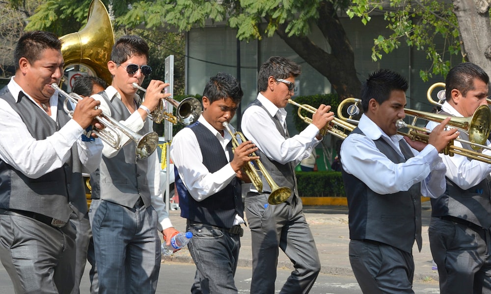 2 men playing trumpet during daytime