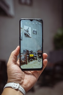 A hand holding a smartphone displaying the furniture identification app scanning a stylish chair.