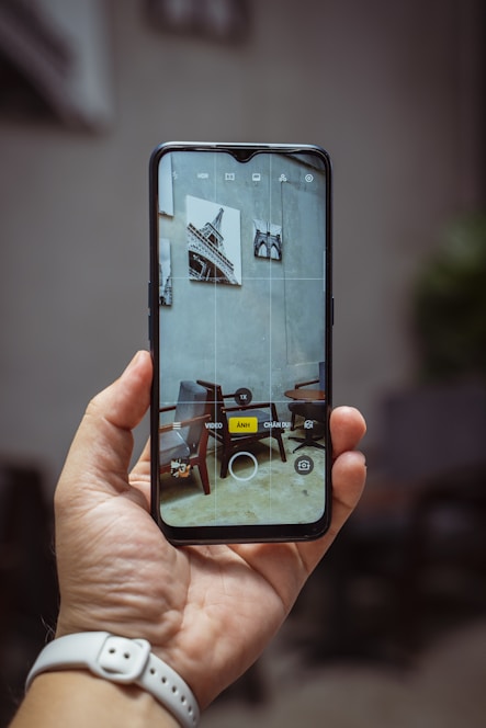A hand holding a smartphone displaying the furniture identification app scanning a stylish chair.