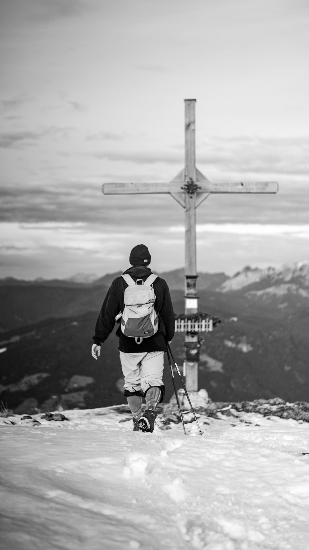 man in black and white jacket and black knit cap standing on rock