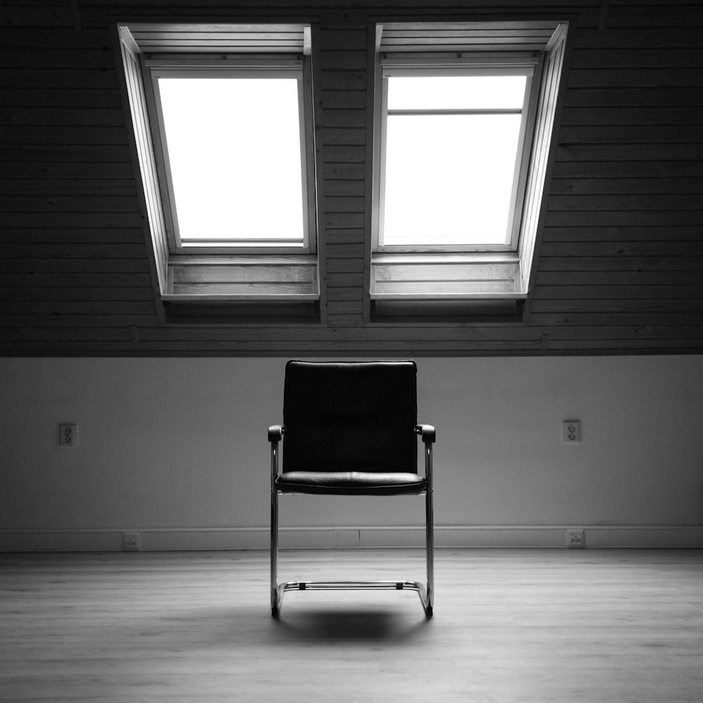 grayscale photo of chair near window