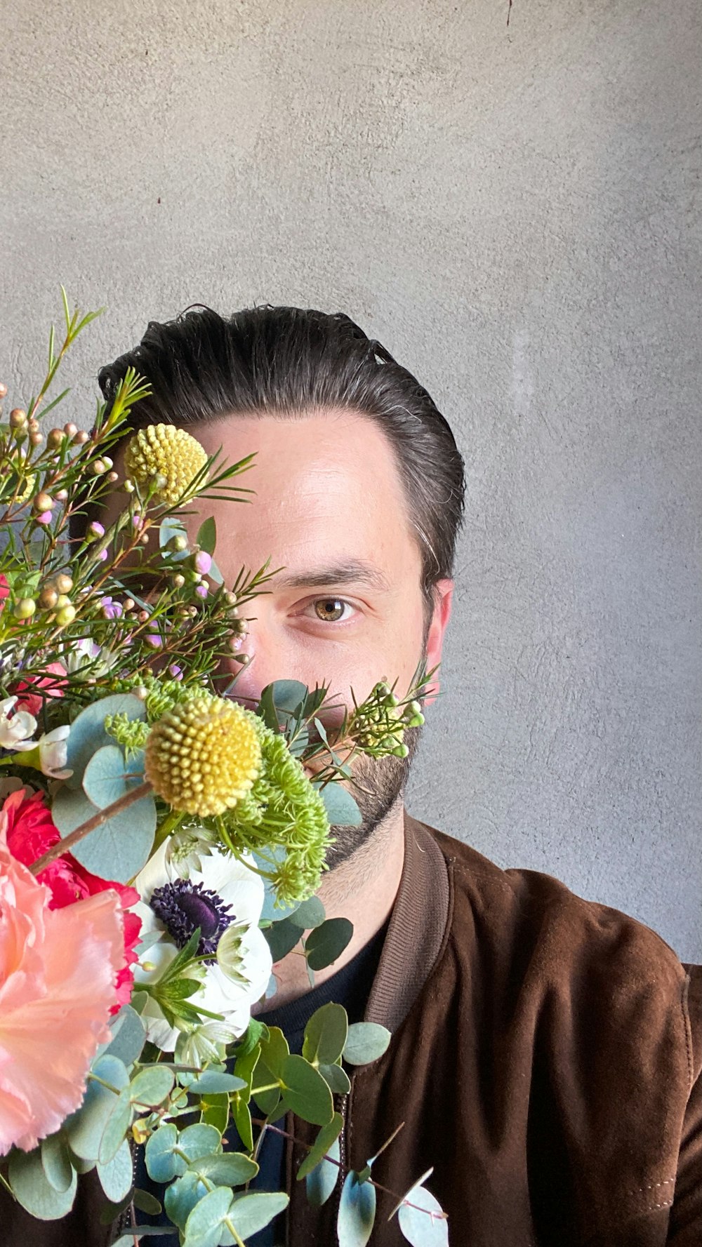 man in brown shirt holding yellow and green flower bouquet