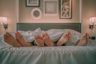person lying on bed covered with white blanket