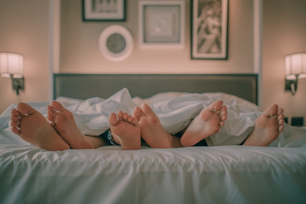 person lying on bed covered with white blanket